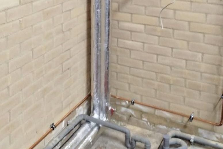 Insulated risers against a brick wall in a plant room