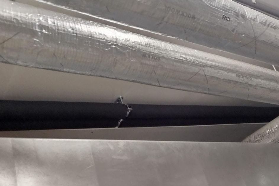 Foil-faced insulated pipe runs passing over a duct in a plant room
