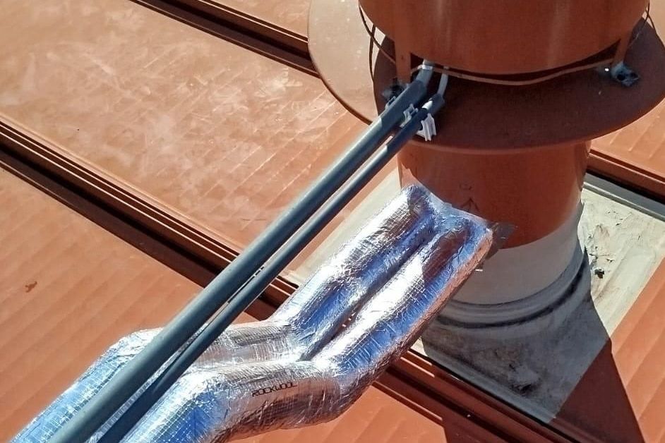 Insulated pipework running to a flue on a tiled roof